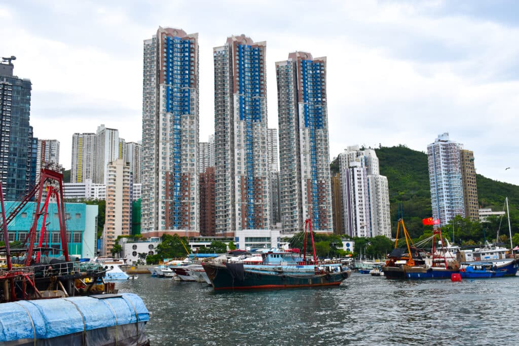 3 tall blocks of flats with harbour in front. Fishing boats on the water