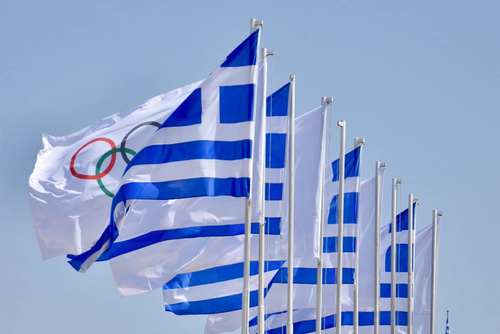 Row of Greek Flags alternated with white Olympic Rings flags