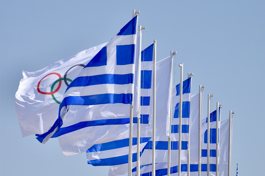 Row of Greek Flags alternated with white Olympic Rings flags