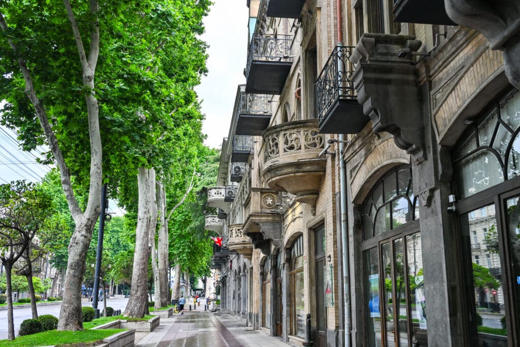 Boulevard street with trees on left and buildings with balconies to the right
