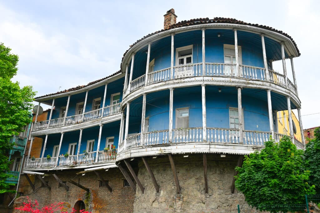 Circular blue two-story house with white balconies on stone foundations