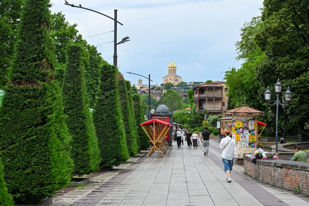 Looking down a street - trees to the left. Tall church on hill in front.