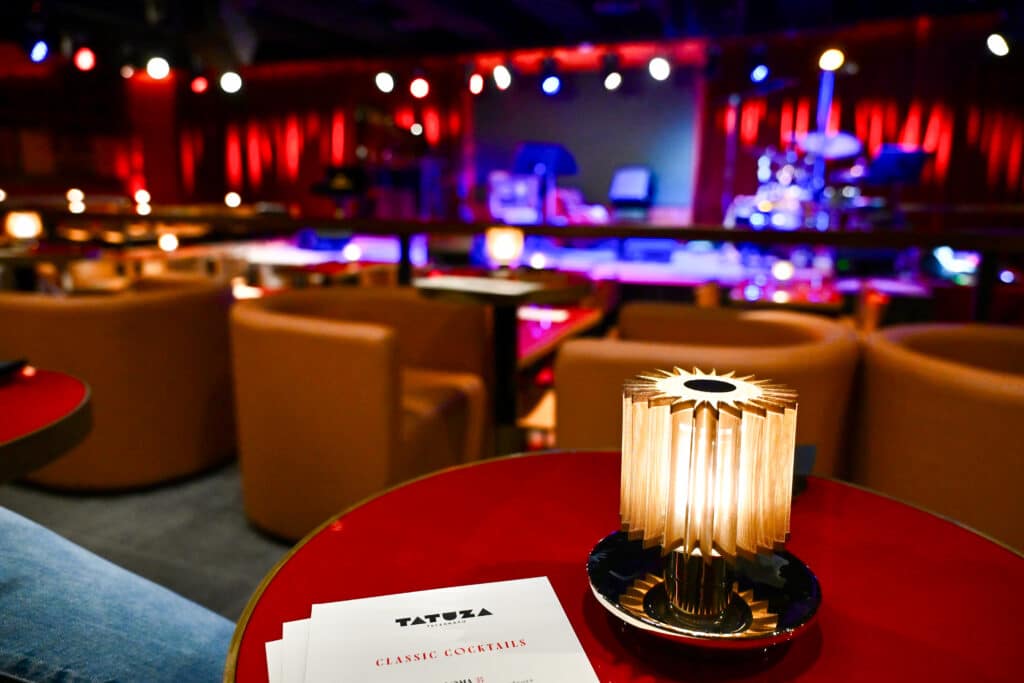A small table lamp on red circular table with Jass club layout behind
