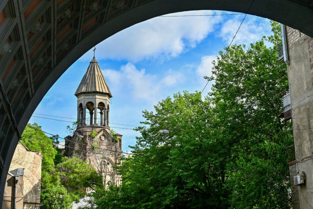 Looking through an arch to the tower of a small church