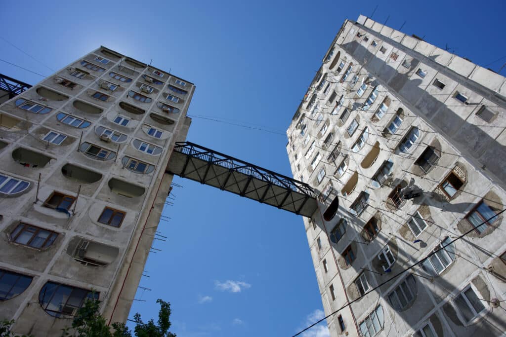 Looking up at two blocks of flats lined by an iron walkway