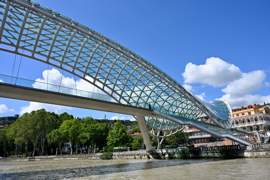 A white metal and glass arch bridge over river