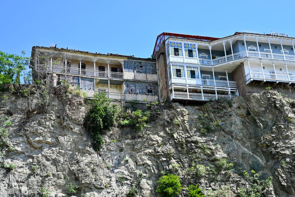Looking up at old wooden houses with balconies overhanding a cliff