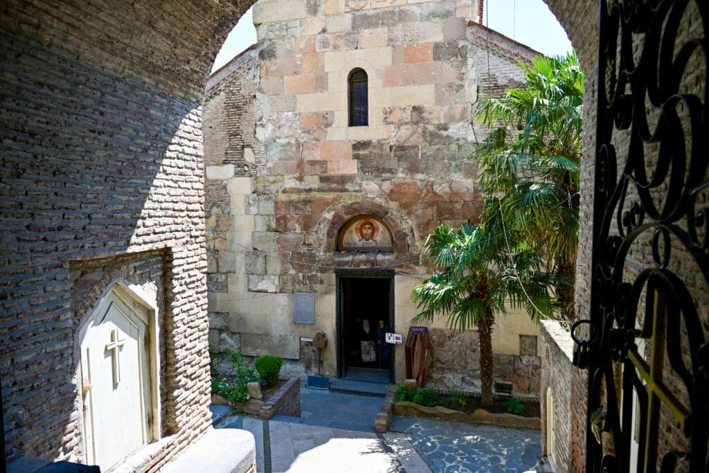 looking down steps to old stone church with painting of Jesus over door