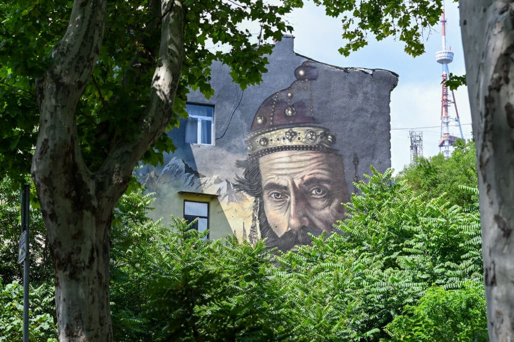 Mural of a King's face on side of a building. Through trees