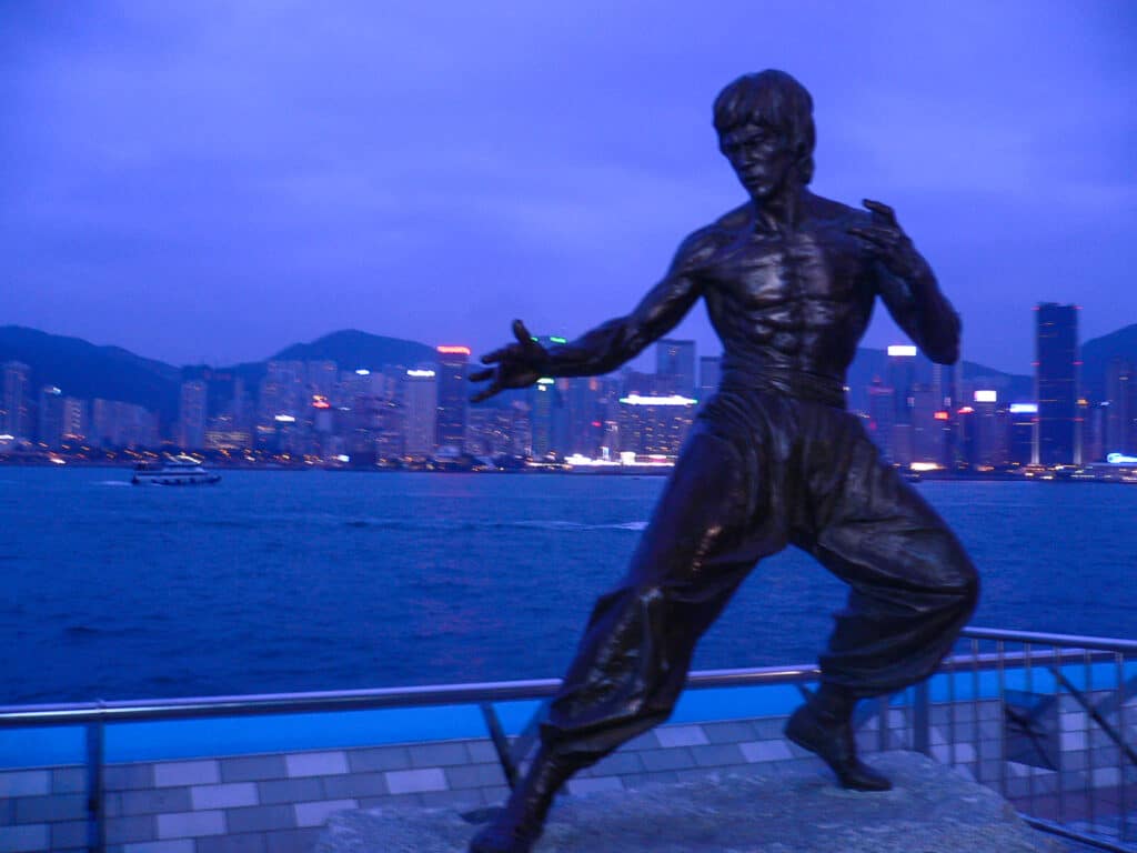 Statue of Bruce Lee at night with city in background