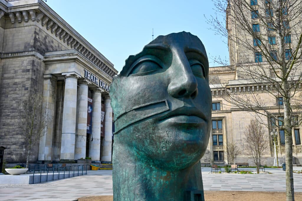 large statue of human face in front of old building