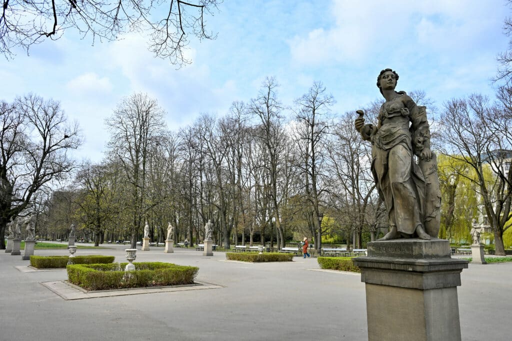 Statue of a lady on a plinth to right. Gardens to the left