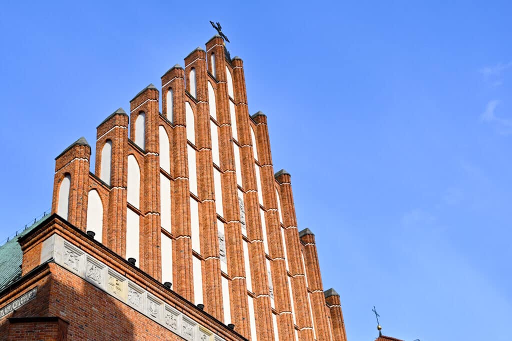 Looking up at a red brick gable roof. Blue sky behind