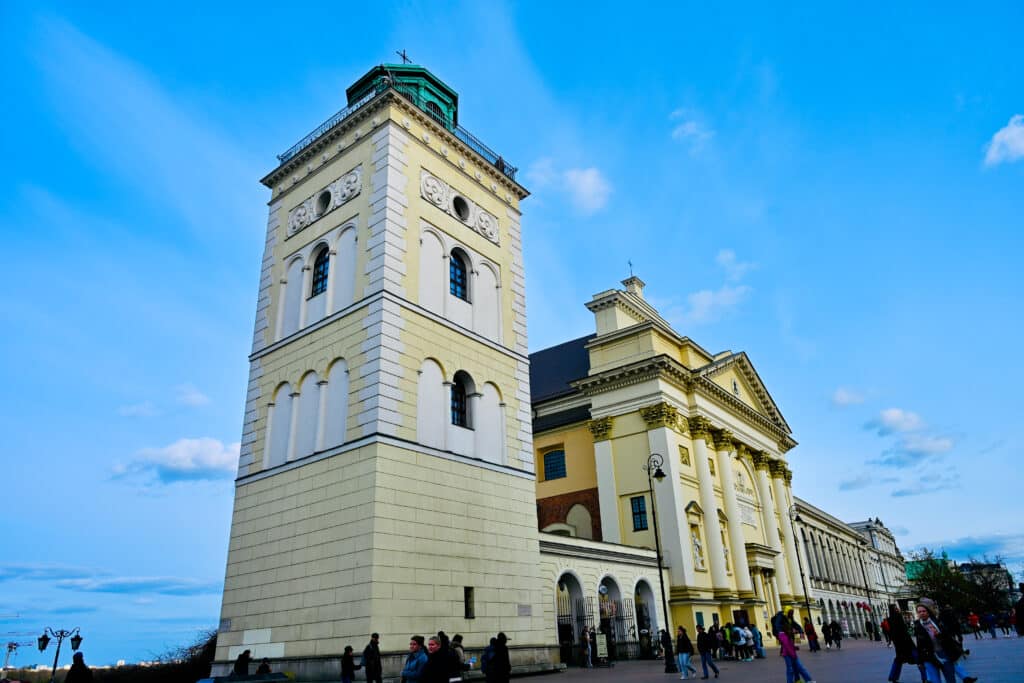 Looking up a square tower and church painted yellow