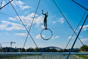 Metal acrobat sculpture on river bridge