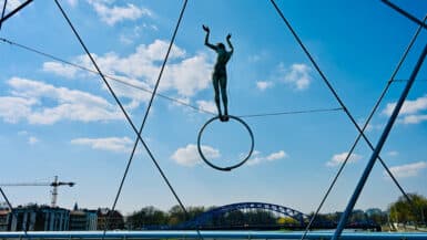 Metal acrobat sculpture on river bridge