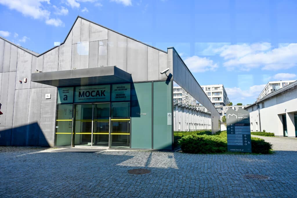 Old factory building with glass doors saying MOCAK over the door