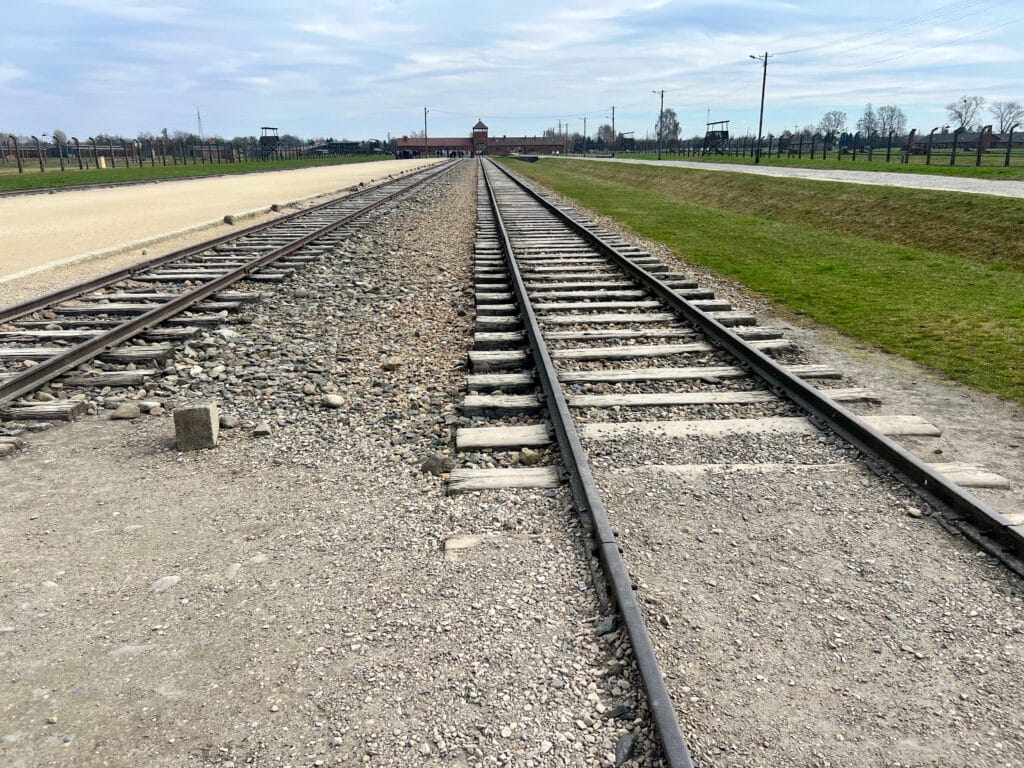 Looking down railway tracks to a wide building at the top.