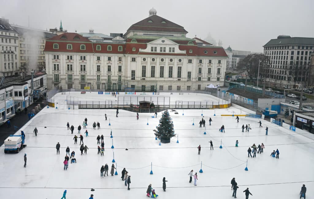Looking down on an ice-rink with large palatial building in the background.