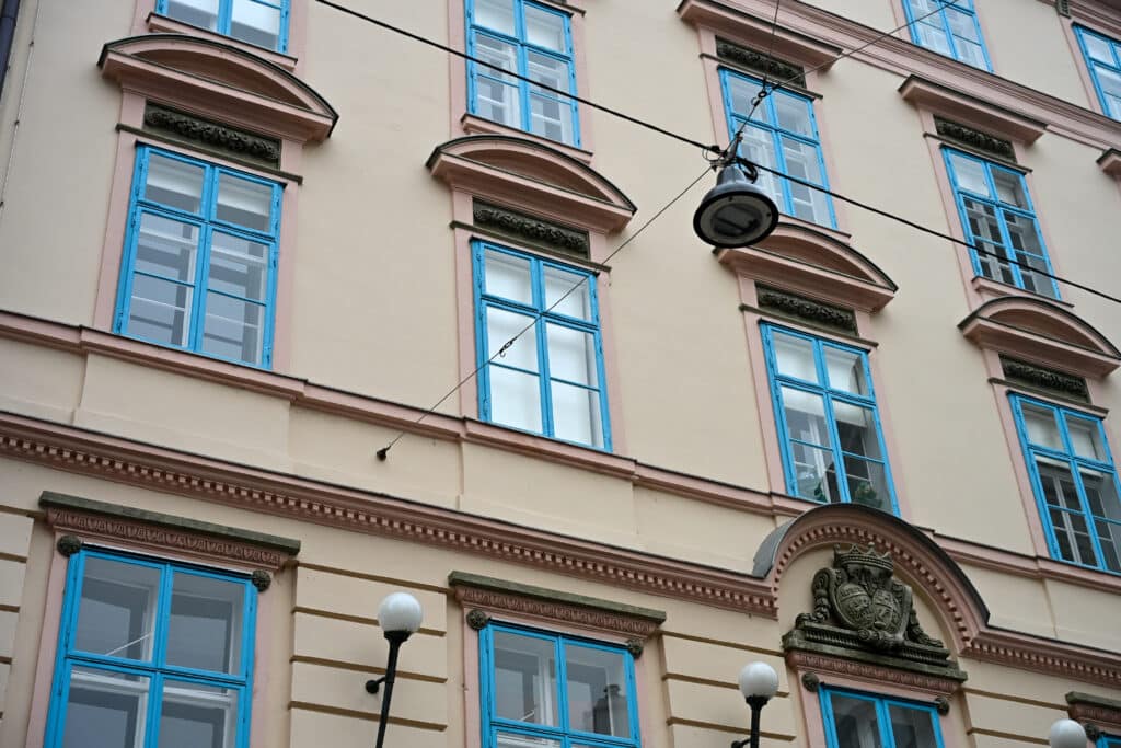 Peach coloured walls with four storeys of blue framed rectangular windows.