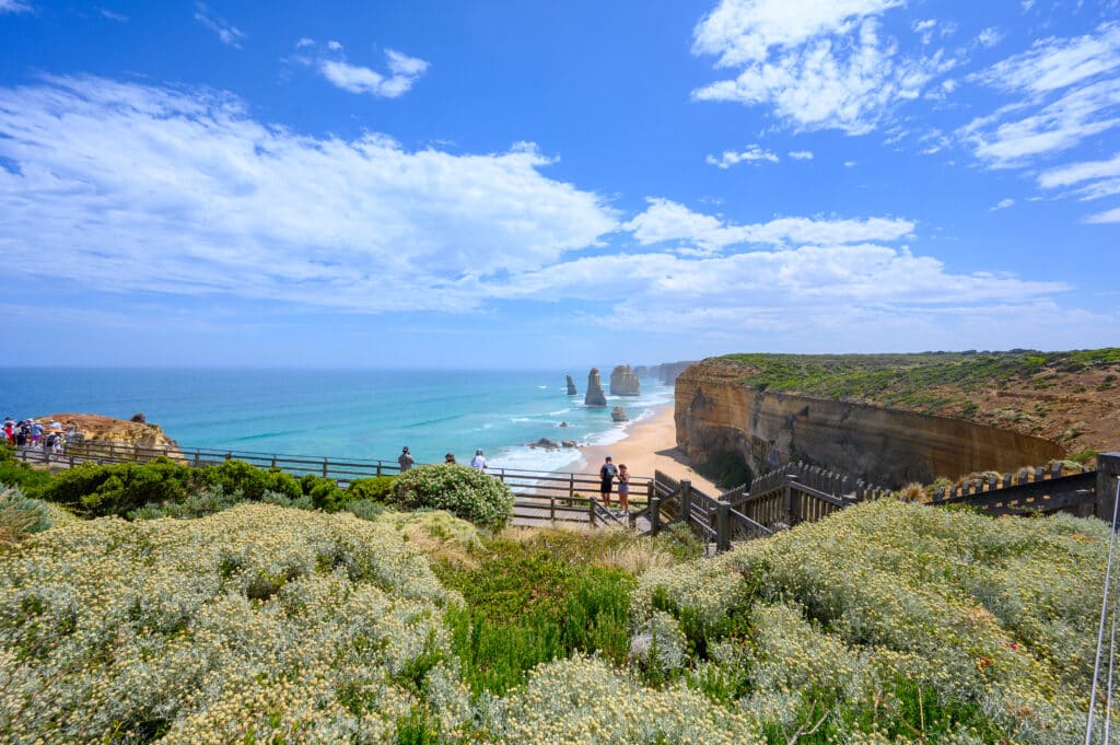 Visitors stand on timber viewing platforms above the beach and limestone stacks at the Twelve Apostles, Victoria.