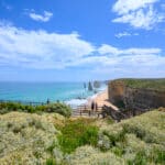 Visitors stand on timber viewing platforms above the beach and limestone stacks at the Twelve Apostles, Victoria.