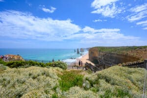 Visitors stand on timber viewing platforms above the beach and limestone stacks at the Twelve Apostles, Victoria.