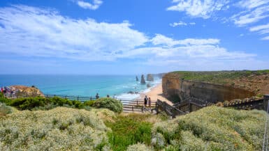 Visitors stand on timber viewing platforms above the beach and limestone stacks at the Twelve Apostles, Victoria.