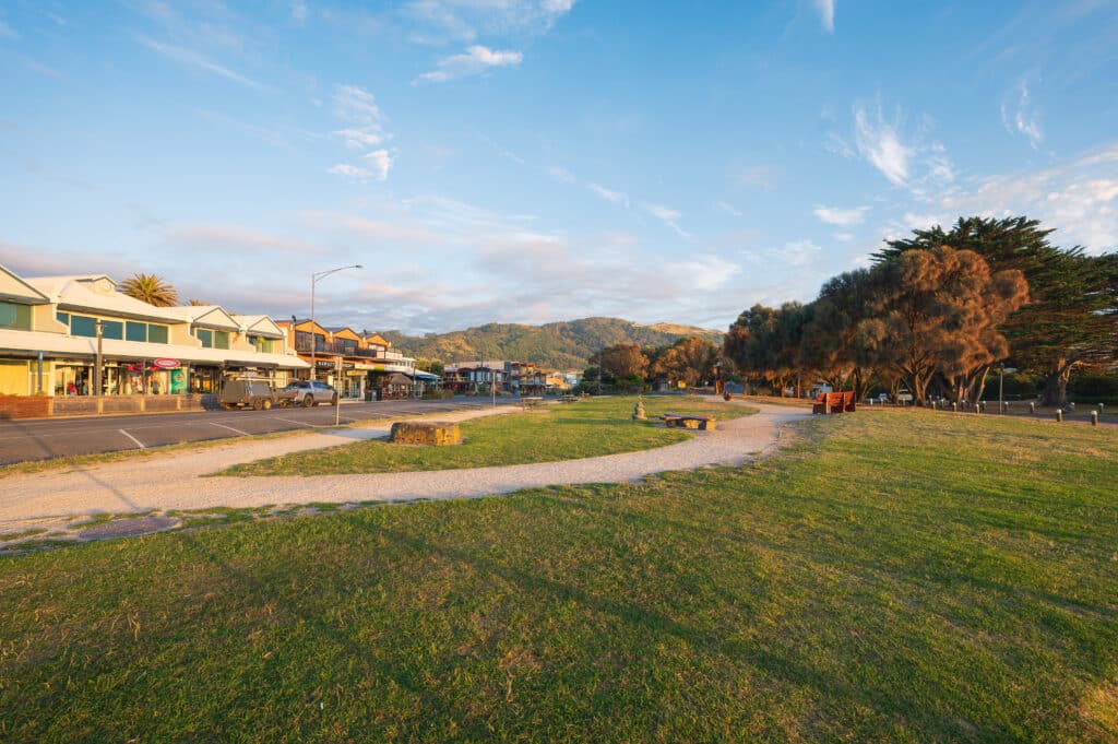 Shops face Apollo Bay’s grassy foreshore, where winding paths and benches catch the warm morning light.