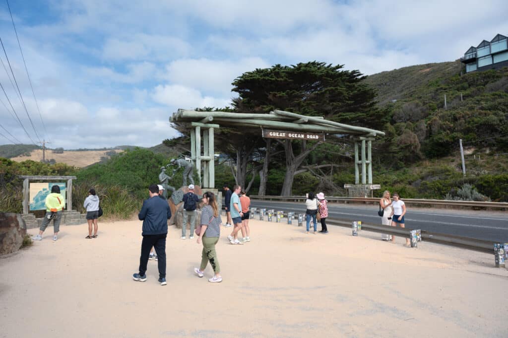 Visitors gather beside The Diggers sculpture and information boards at the Great Ocean Road Memorial Arch in Eastern View.