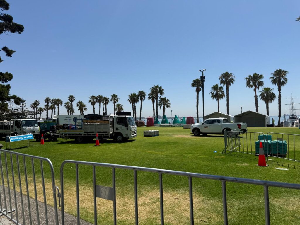 Trucks, temporary fencing and tents occupy the palm-lined waterfront lawns at Steampacket Gardens in Geelong.