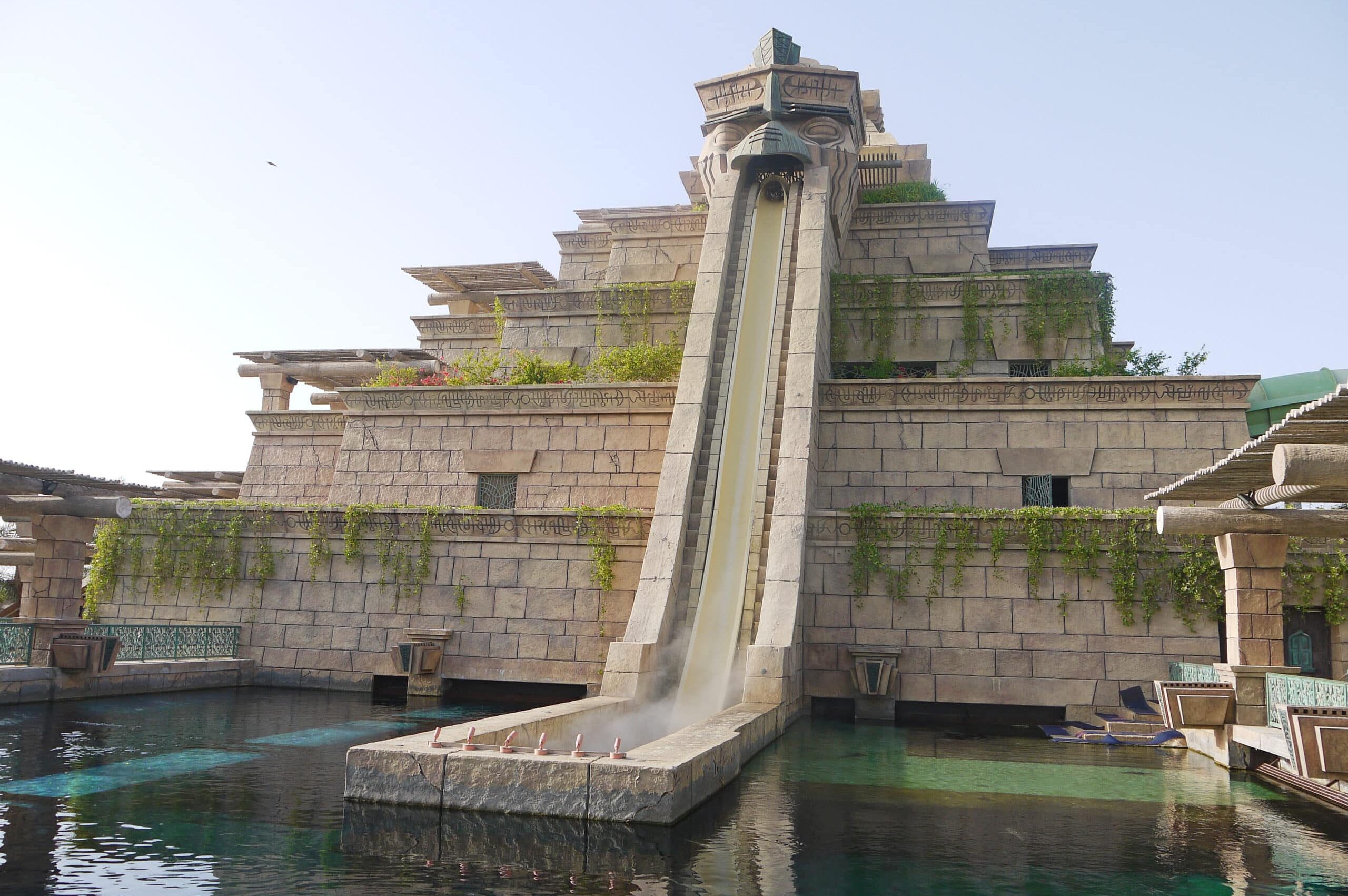 Pyramid shaped structure with water slide on the front down to the pool